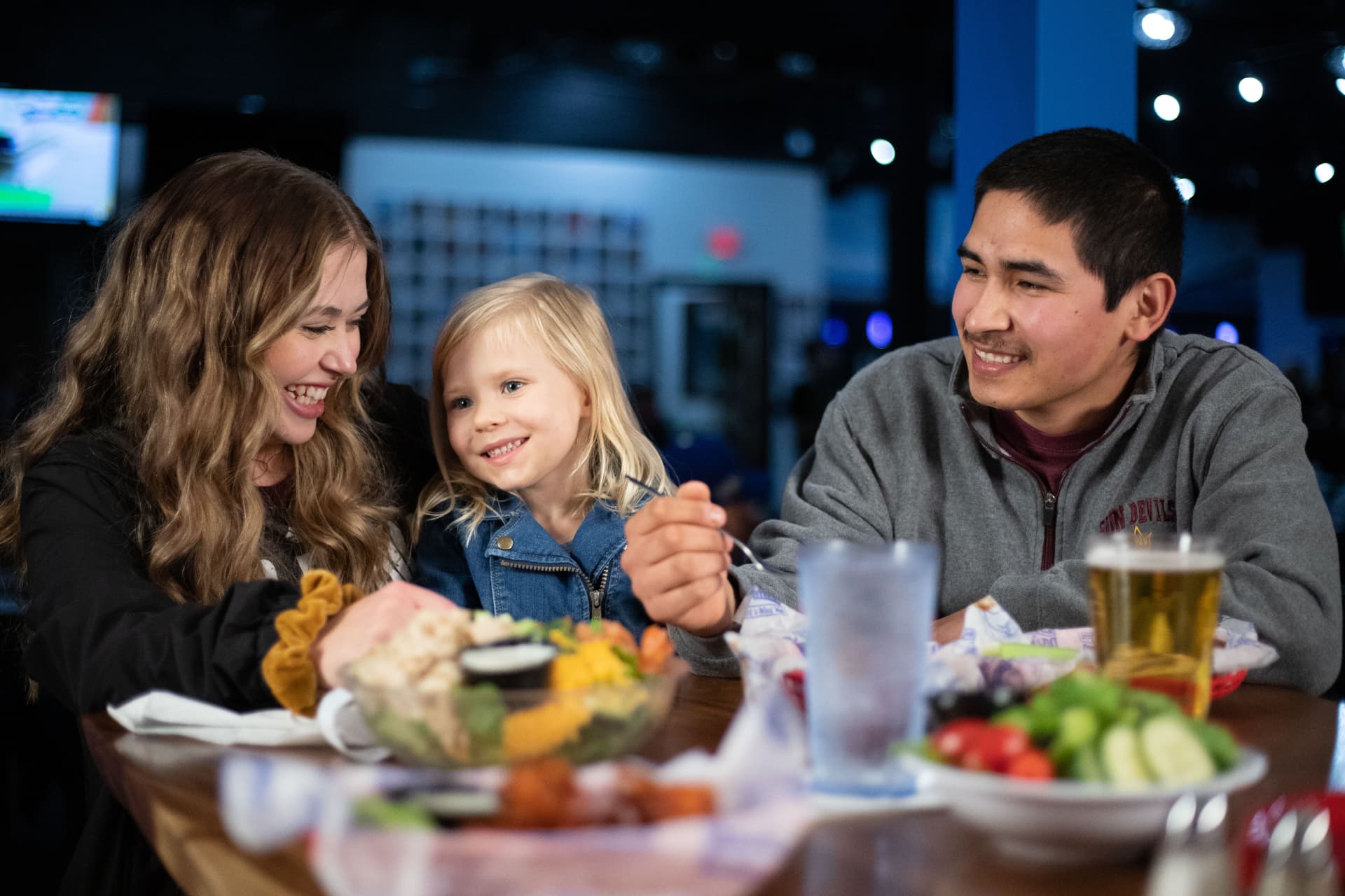 A family sharing wings and salad in the dining room at The Dirty Buffalo